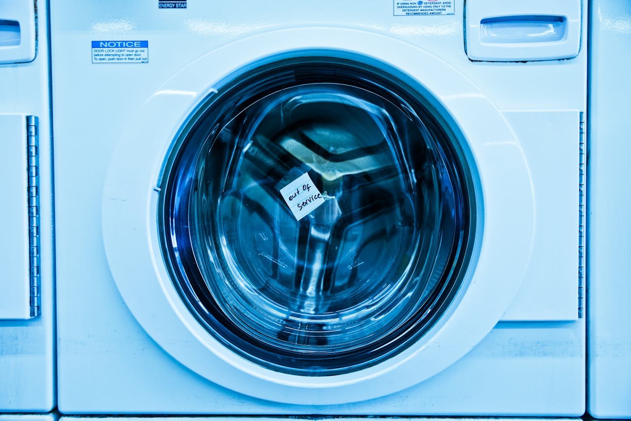 Close-up of an out-of-service washing machine in a laundromat with a blue tint.